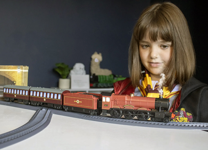 Young child looking at their model of the Hogwarts Express train. 
